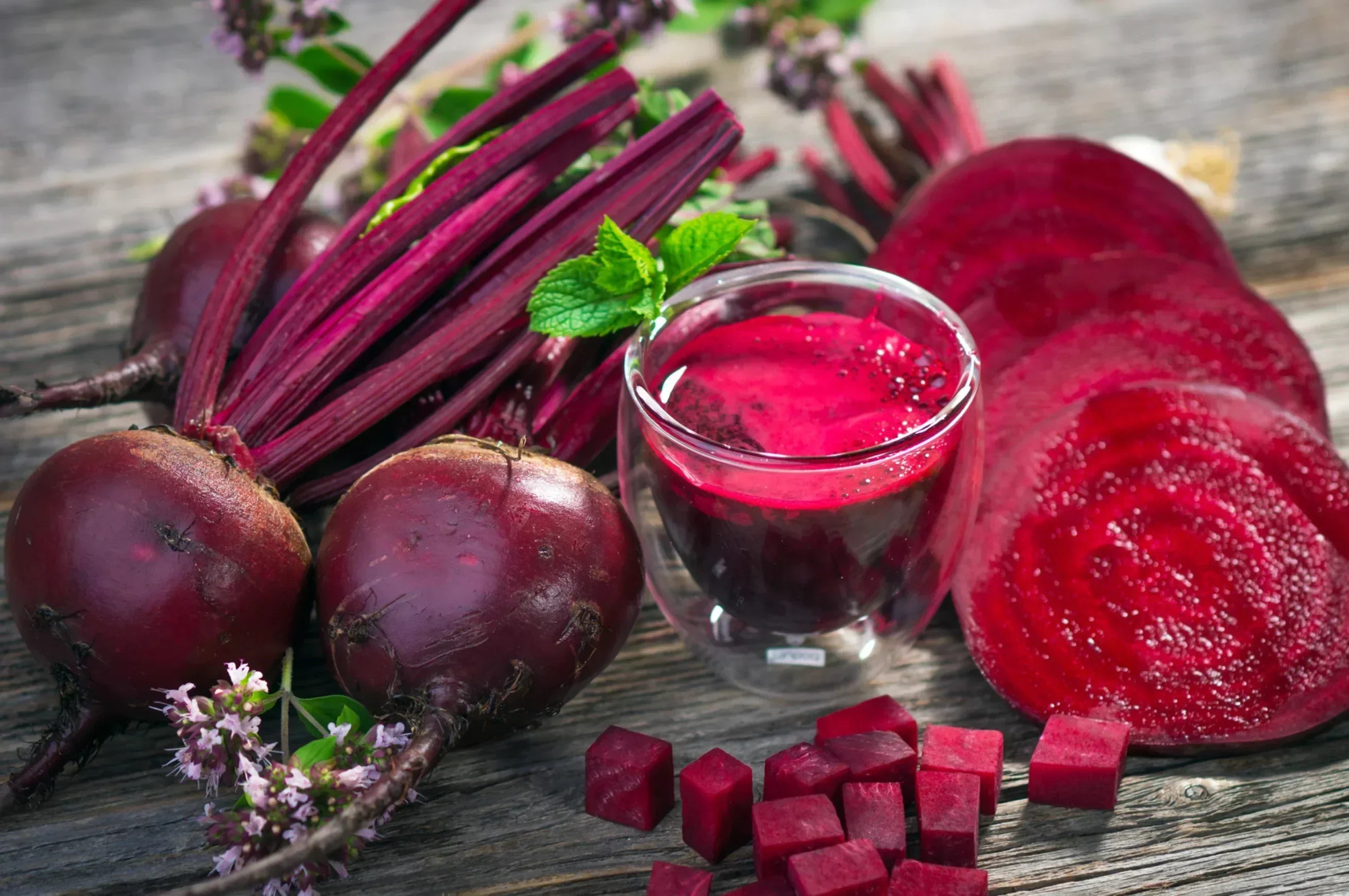 Fresh beets, juice, slices, and cubes on wood table, featuring stamox beetroot powder ingredients
