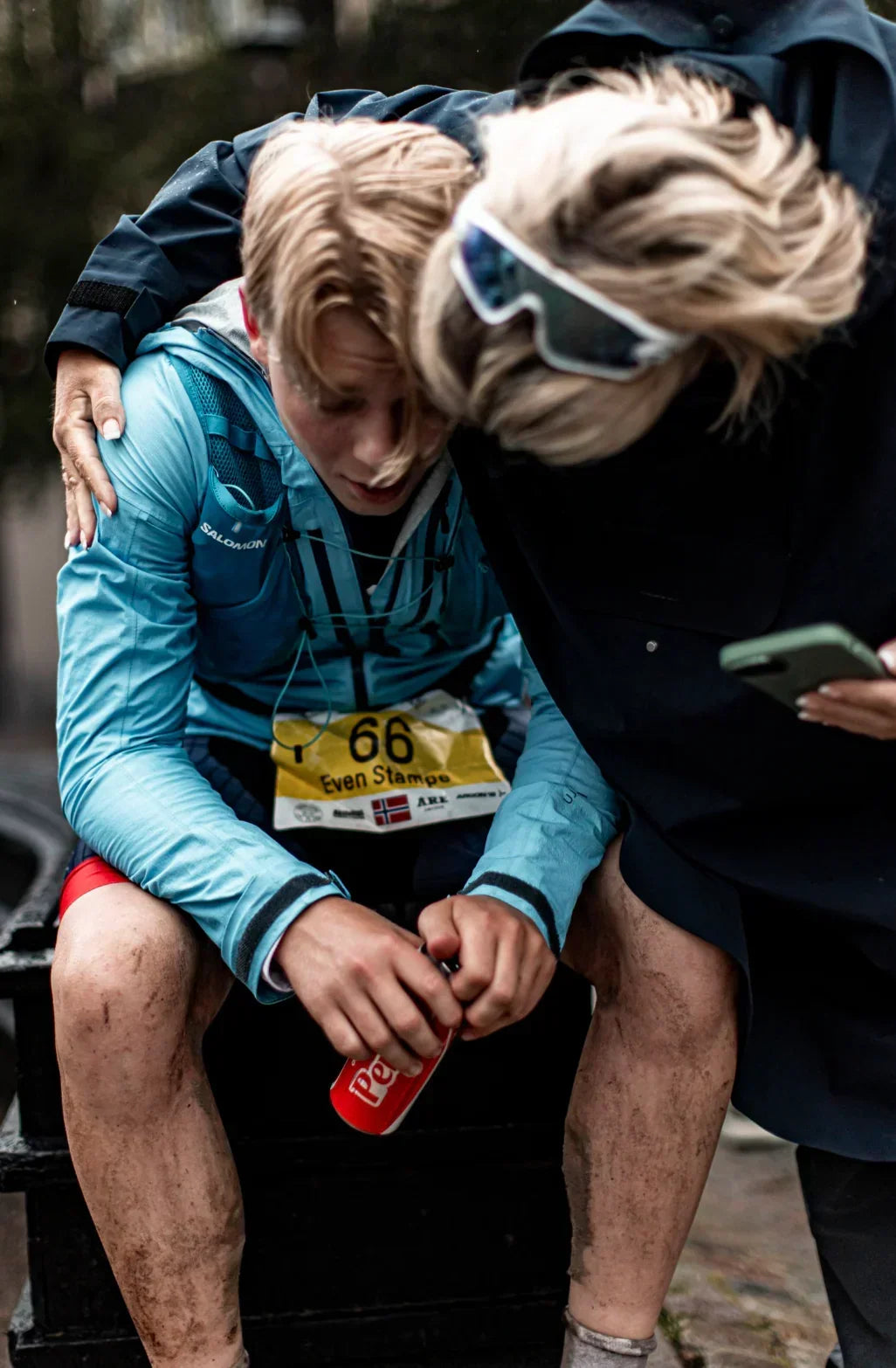 Two individuals sitting together, one holding a phone, with a focus on outdoor activity. Rolf Solheimdal Johansen, a seasoned triathlete with multiple Norwegian and World Championship gold medals in Winter Triathlon, recently completed the challenging Swedeman Xtreme Triathlon.
