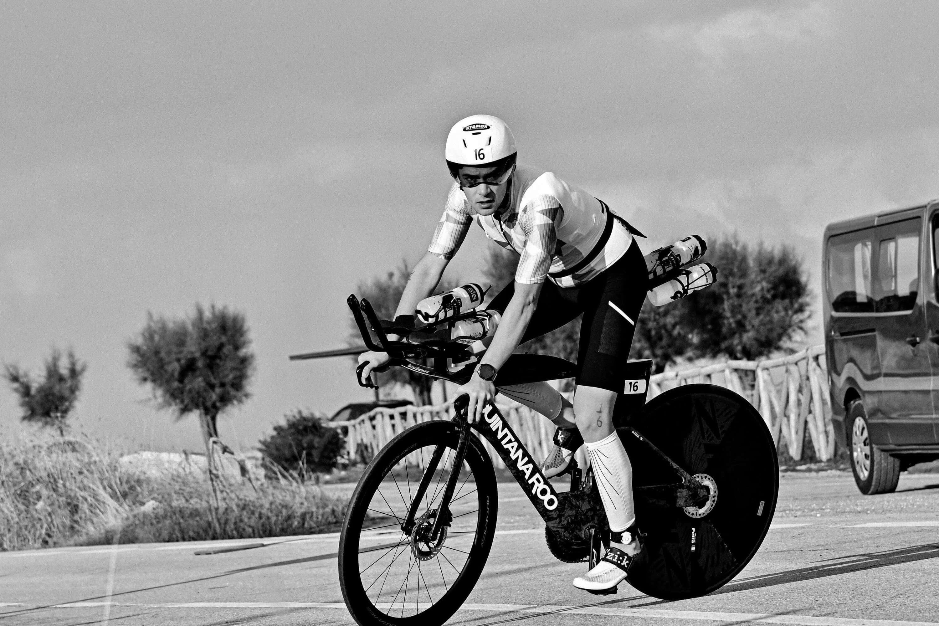 Ironman cyclist on racing bike wearing helmet with stamox beetroot powder logo during triathlon