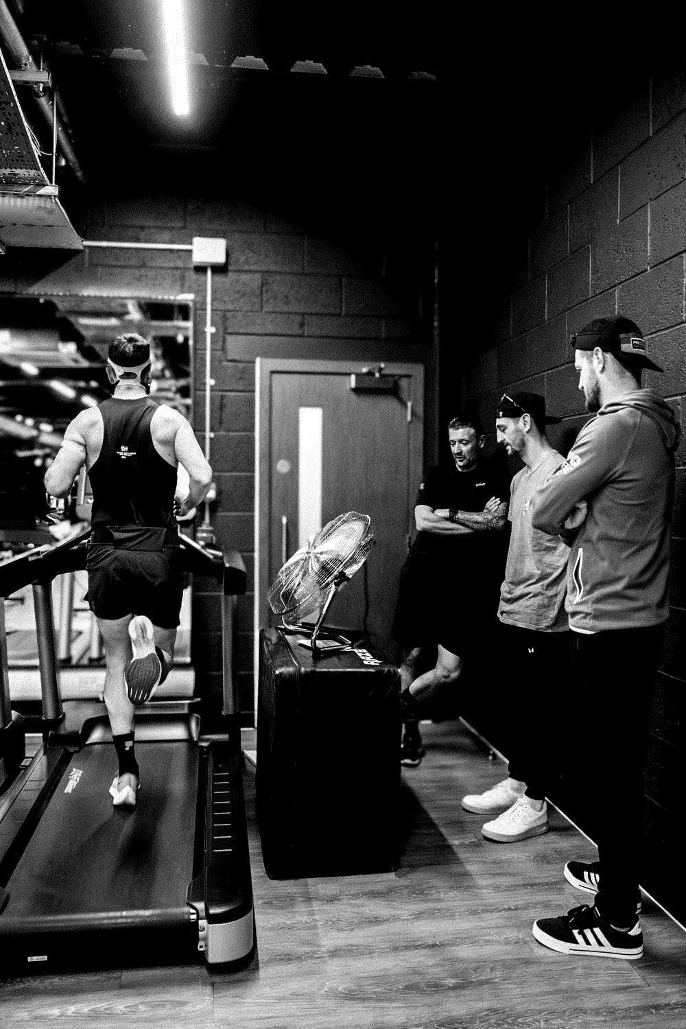 Athlete running on treadmill with group watching, stamox beetroot powder endurance training