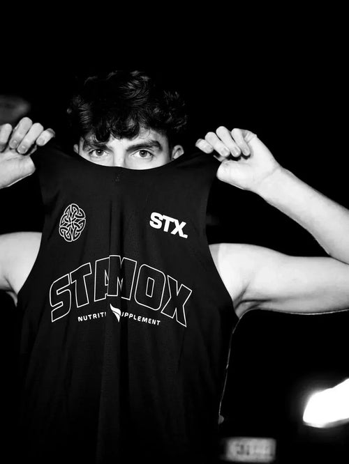 Man holding up shirt with Stamox Beetroot Powder branding, fitness supplement promotion