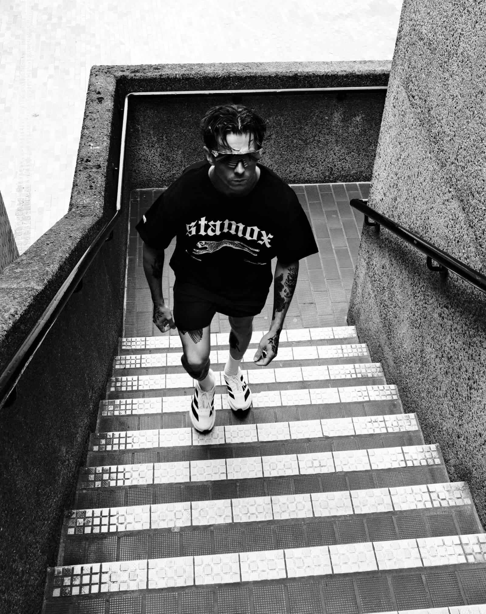 Athlete in stamox beetroot powder shirt climbing stairs, promoting endurance and energy.