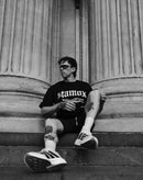Man wearing stamox beetroot powder shirt, sitting on stone steps, sporty and urban style
