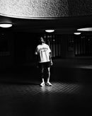 Man in urban setting wearing stamox beetroot powder shirt, standing in dramatic light