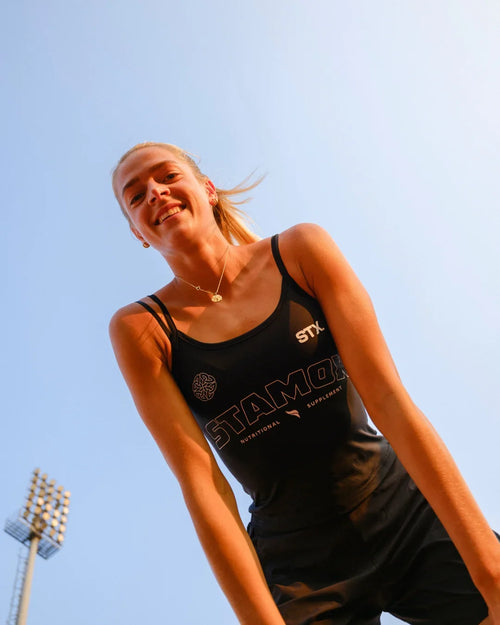 Female athlete outdoors wearing black tank promoting stamox beetroot powder