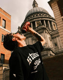 Man outdoors drinking from bottle featuring stamox beetroot powder in urban city setting