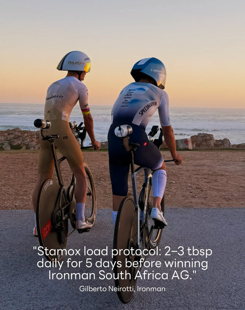 Two cyclists in racing gear by the ocean at sunset promoting Stamox beetroot powder