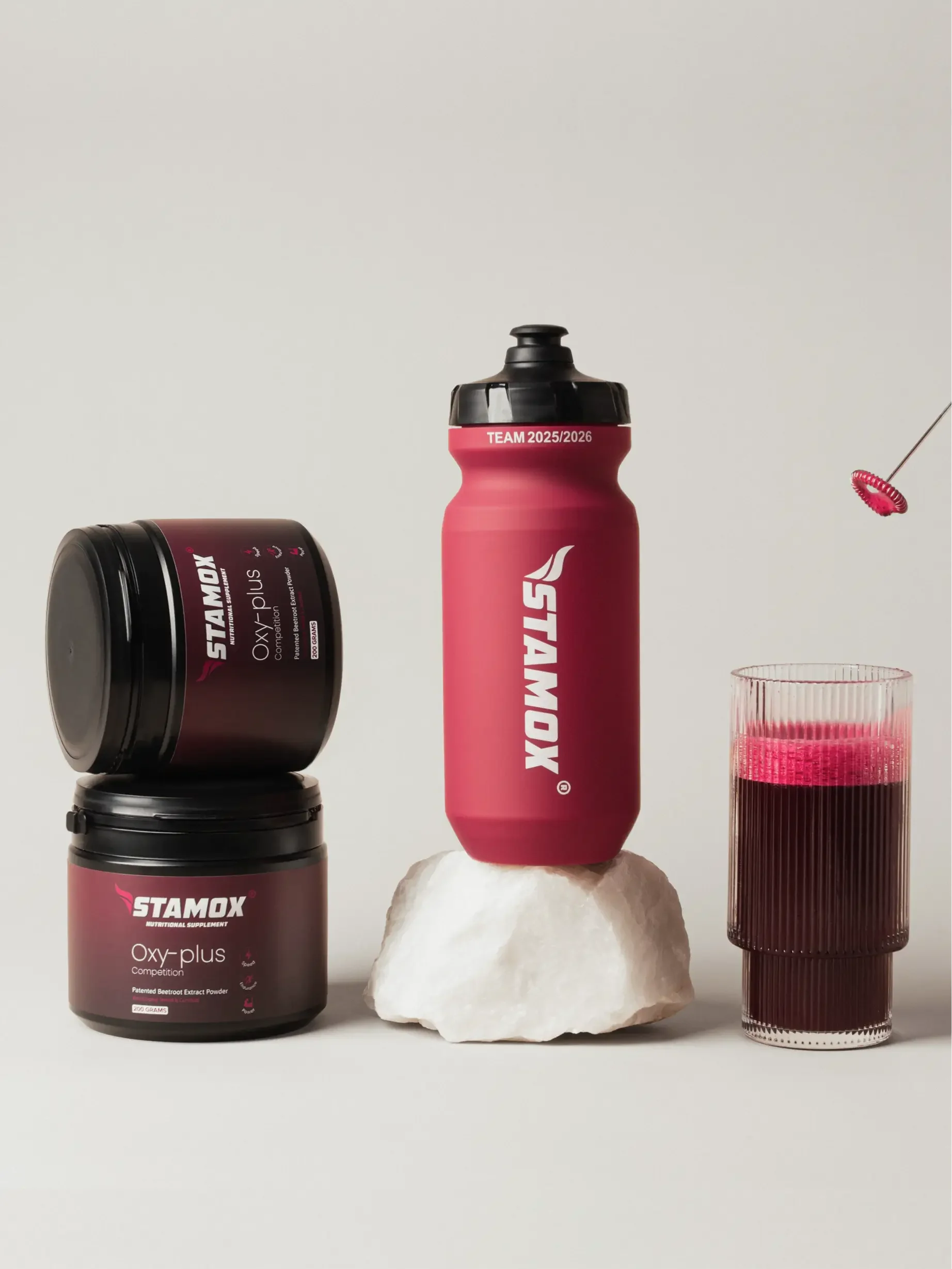 Stamox Oxy-plus beetroot powder jars, red sports bottle, and glass of vibrant beet juice for endurance and recovery