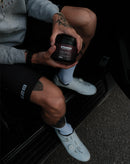 Athlete holding Stamox Oxy-plus beetroot powder supplement, wearing cycling gear and shoes