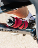 Stamox beetroot powder branded red water bottle on bicycle frame, cyclist in motion