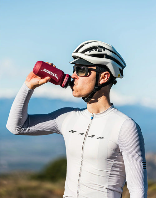 Cyclist drinks from Stamox bottle outdoors, promoting Stamox beetroot powder benefits.