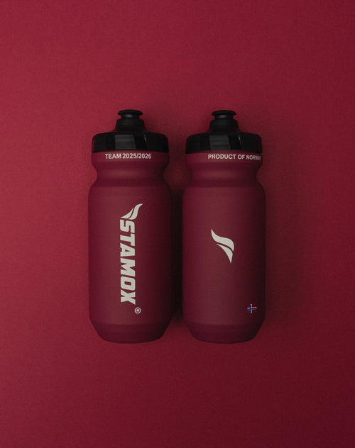 Two red sports bottles with Stamox branding, used for Stamox beetroot powder, on a red background.