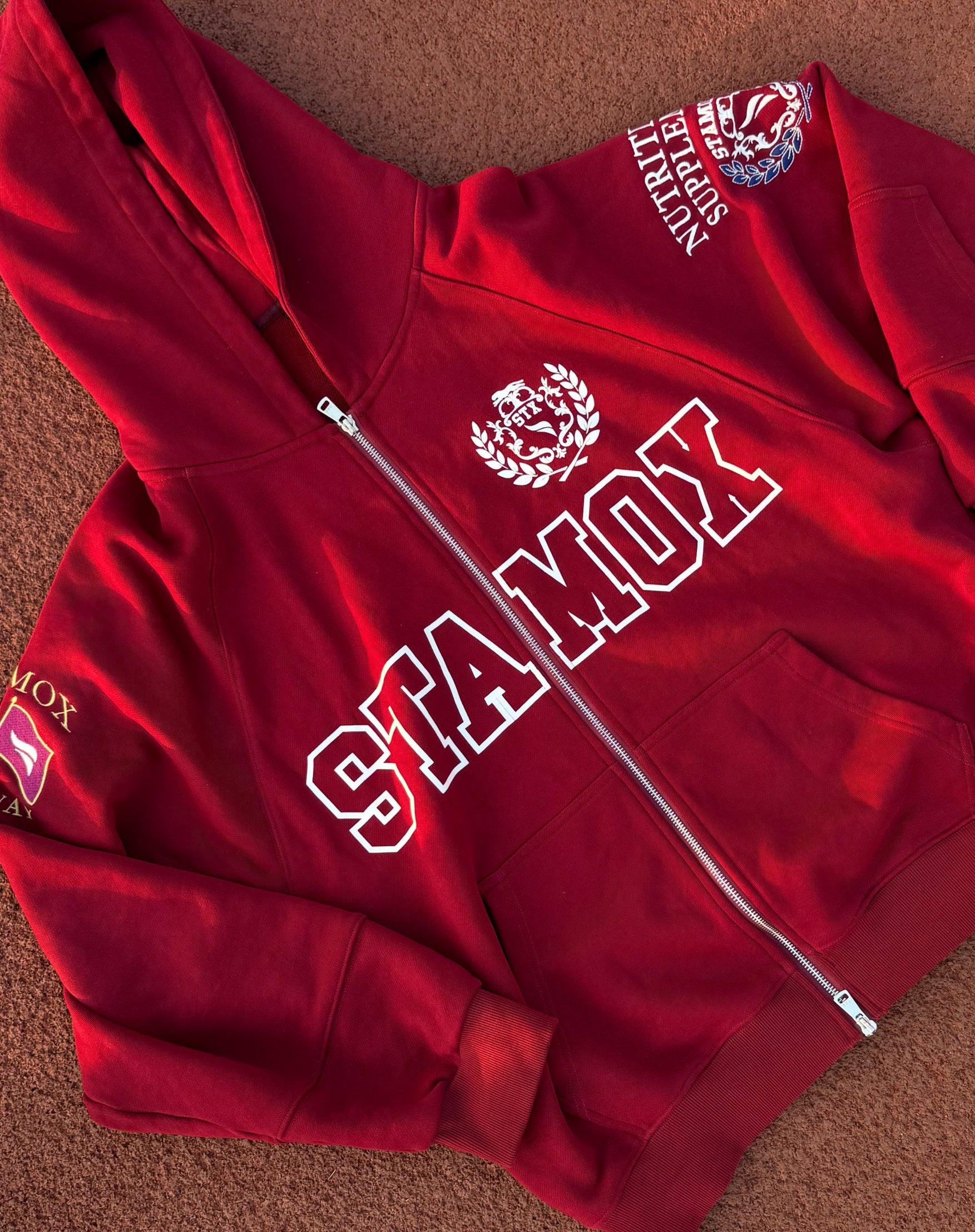 Red hoodie with Stamox Beetroot Powder logo and text, laid flat on brown surface