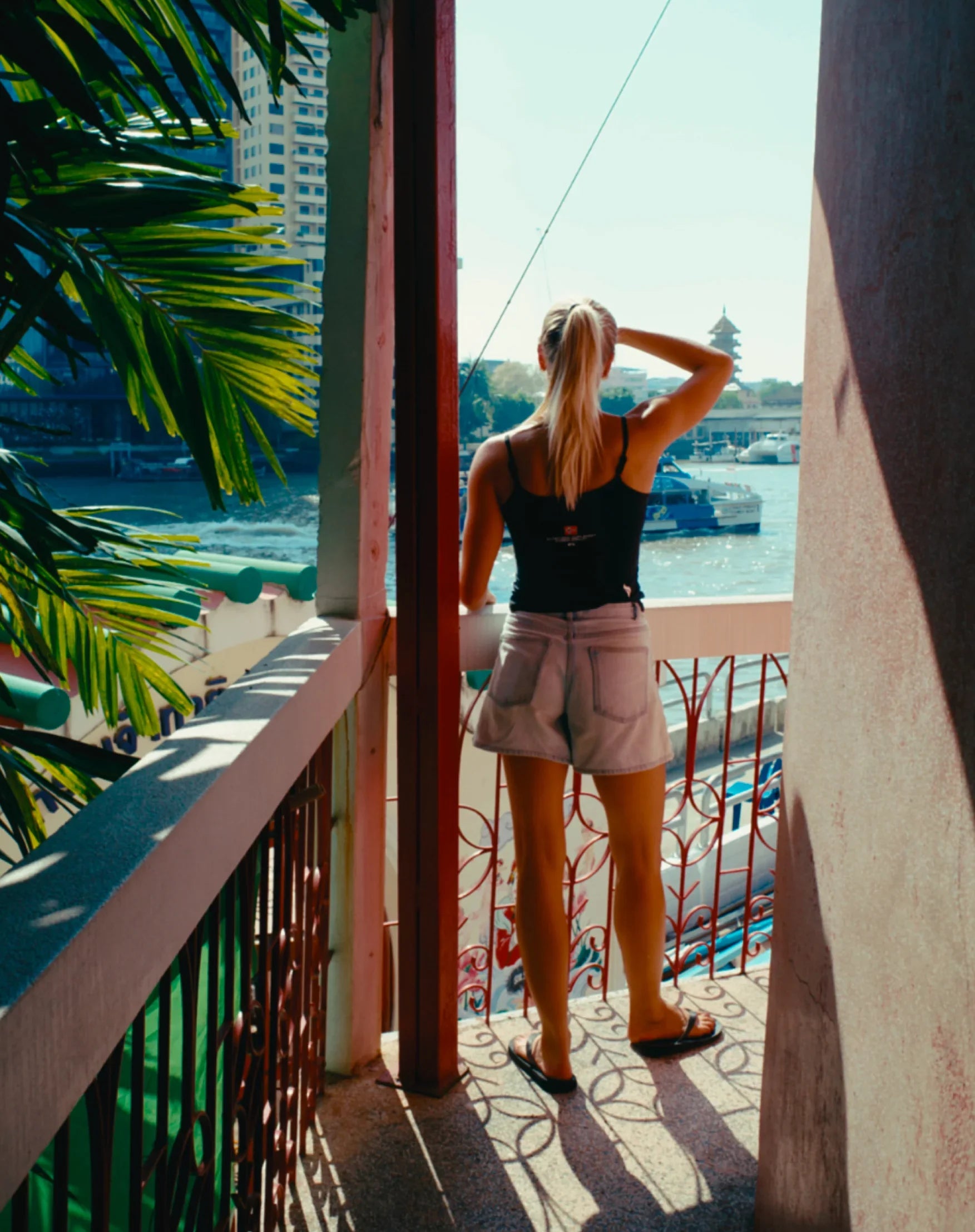 Woman in casual outfit with stamox beetroot powder tank top overlooking river and cityscape