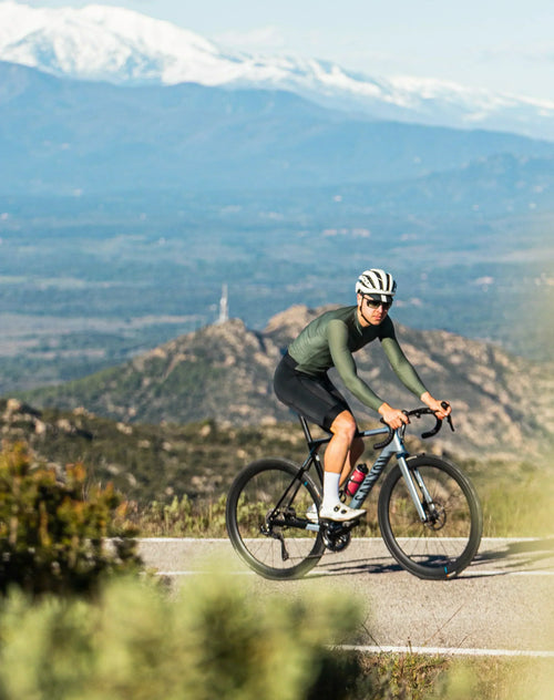 Cyclist riding in mountains with Stamox Beetroot Powder bottle, promoting endurance and VO2 max