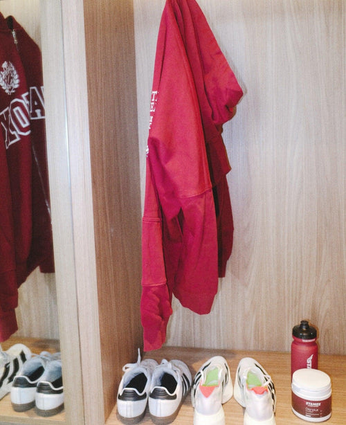 Stamox beetroot powder container and shaker bottle on locker shelf with sneakers and red hoodie