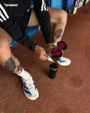 Athlete scooping stamox beetroot powder into a shaker on a track, fitness supplement