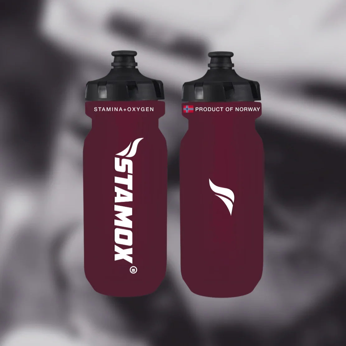 Two maroon water bottles with black lids on a blurred background