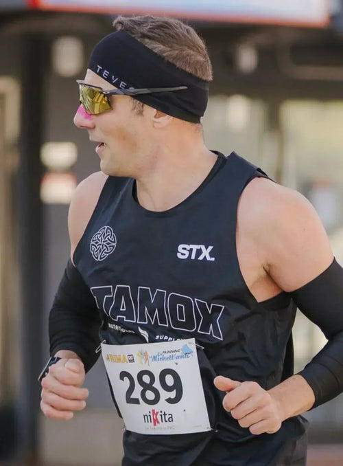 Athlete running in marathon wearing black Stamox Beetroot Powder shirt and race bib 289
