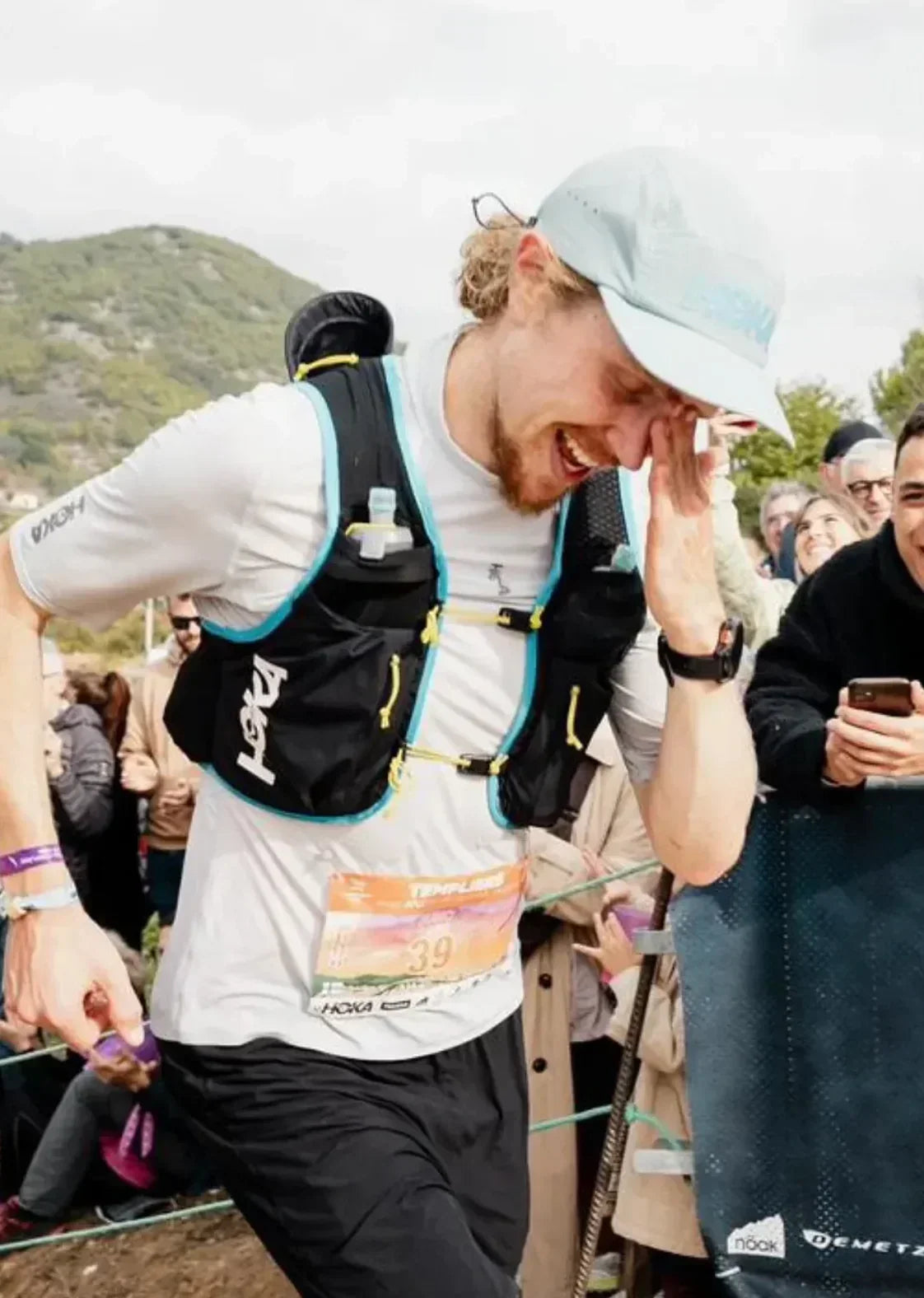 Trail runner finishing race, smiling with crowd, stamox beetroot powder endurance boost