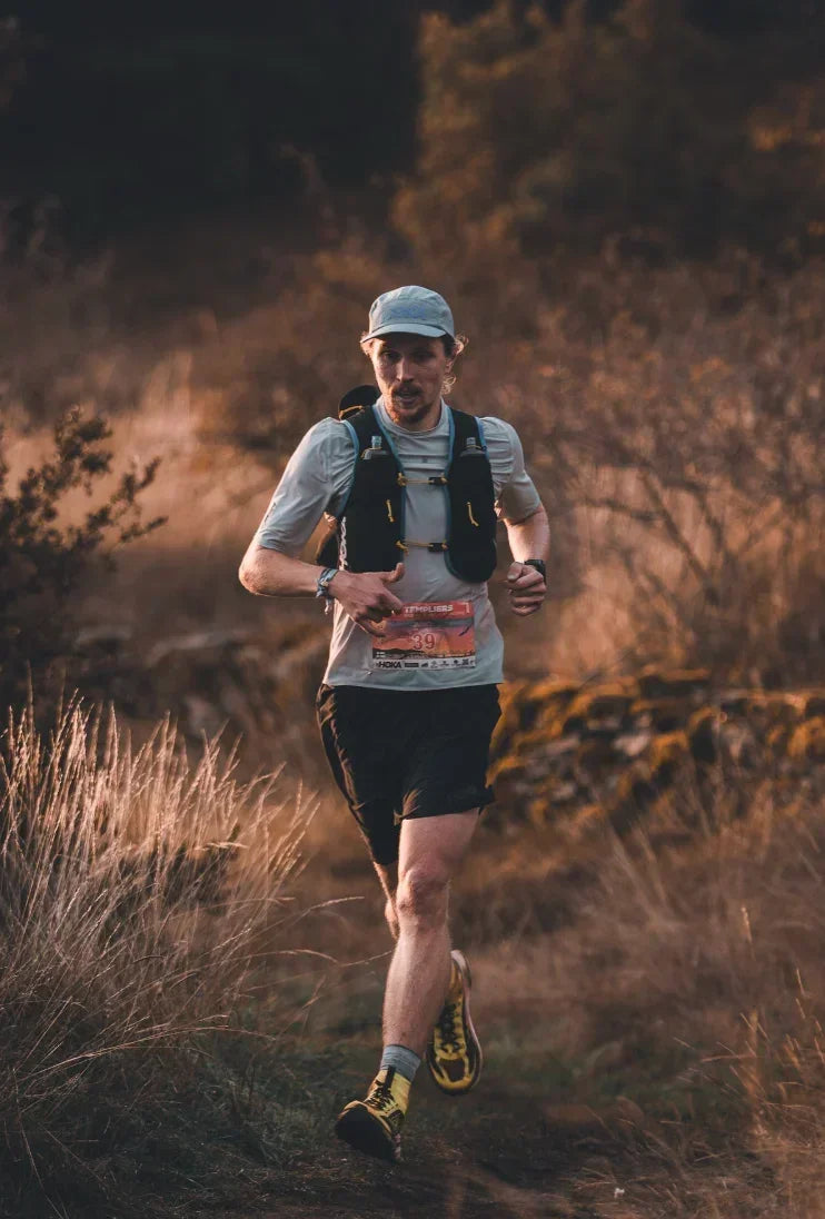 Trail runner outdoors wearing race bib, promoting Stamox Beetroot Powder for endurance