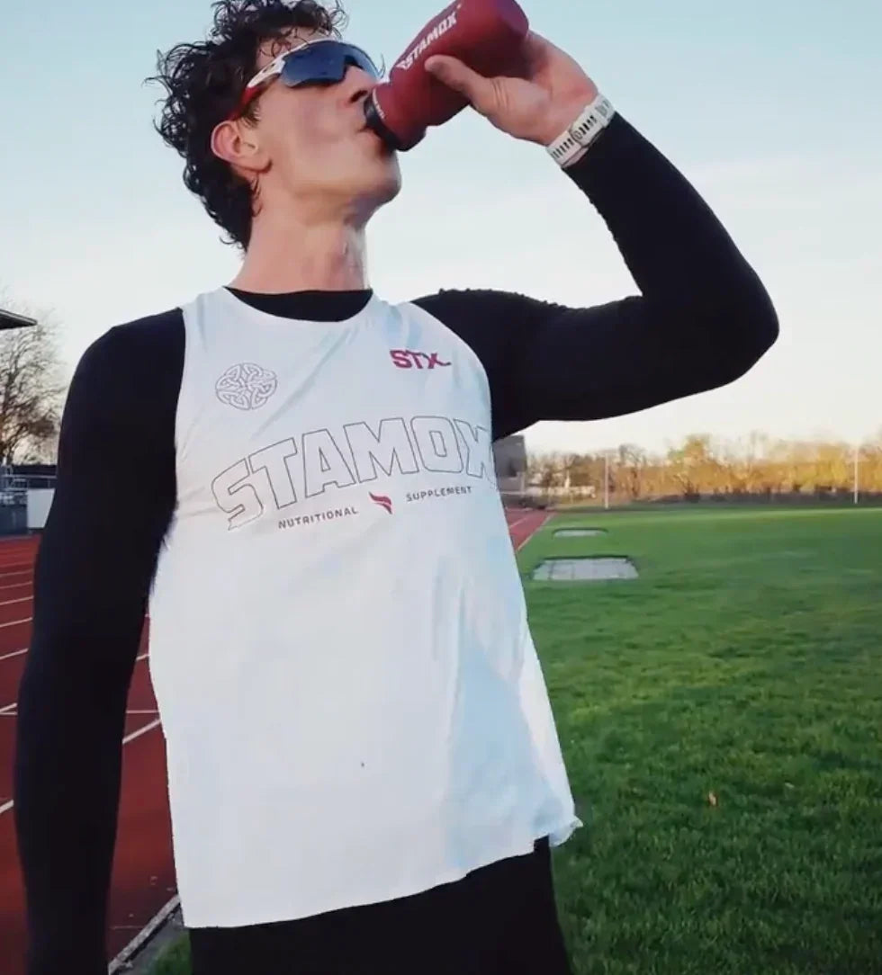 Athlete drinking Stamox Beetroot Powder supplement at outdoor running track