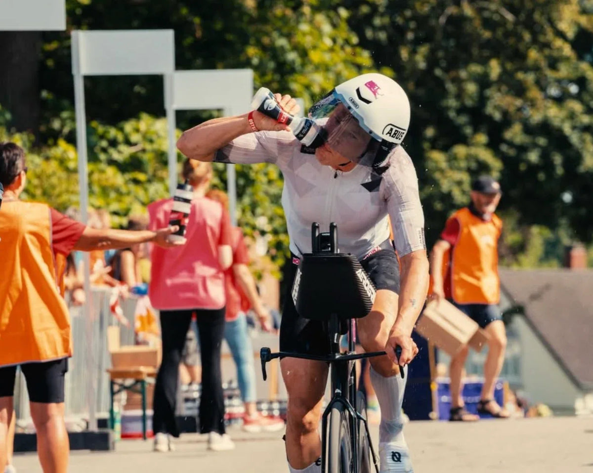 Cyclist in helmet drinking stamox beetroot sport nutrition for vo2 max during a race.