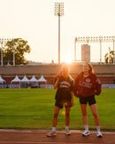Two women athletes on a track field at sunset with stamox beetroot powder drink