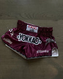 Stamox beetroot powder branded maroon boxing shorts with YOKKAO logo on wooden floor