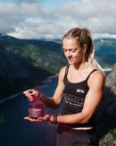 Athlete holding beetroot powder supplement jar with mountain view, boosting endurance and recovery naturally