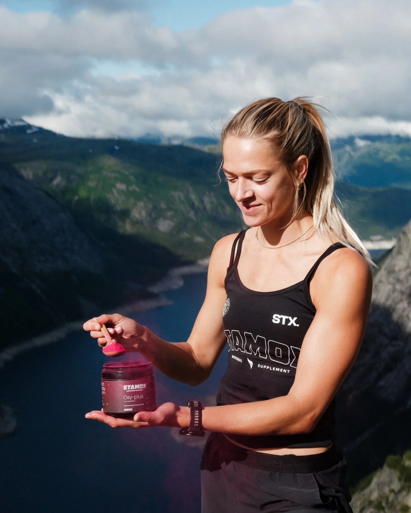 Athlete holding beetroot powder supplement jar with mountain view, boosting endurance and recovery naturally