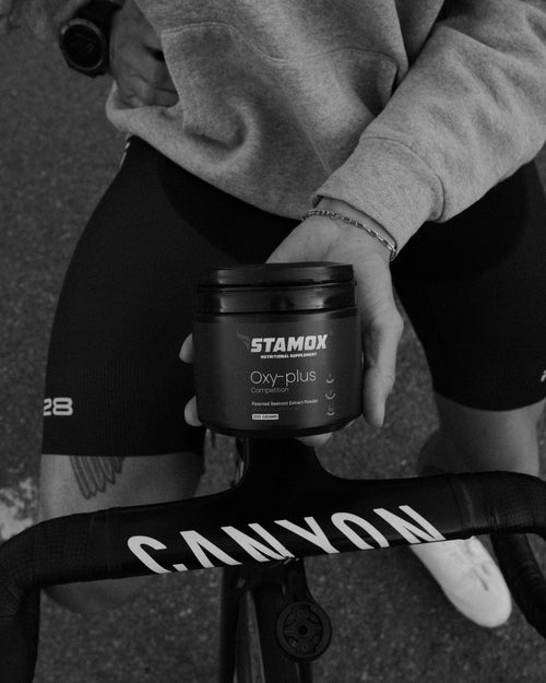 Athlete holding Stamox Oxy-plus beetroot extract powder near Canyon bike, boosting endurance and recovery.