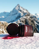 Stamox beetroot powder container open on snowy mountain with red powder spilled.