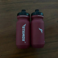 Stamox beetroot powder branded red water bottles on wooden table