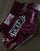 Maroon boxing shorts with 'Yokkao' and Stamox beetroot STX branding on a wooden floor.
