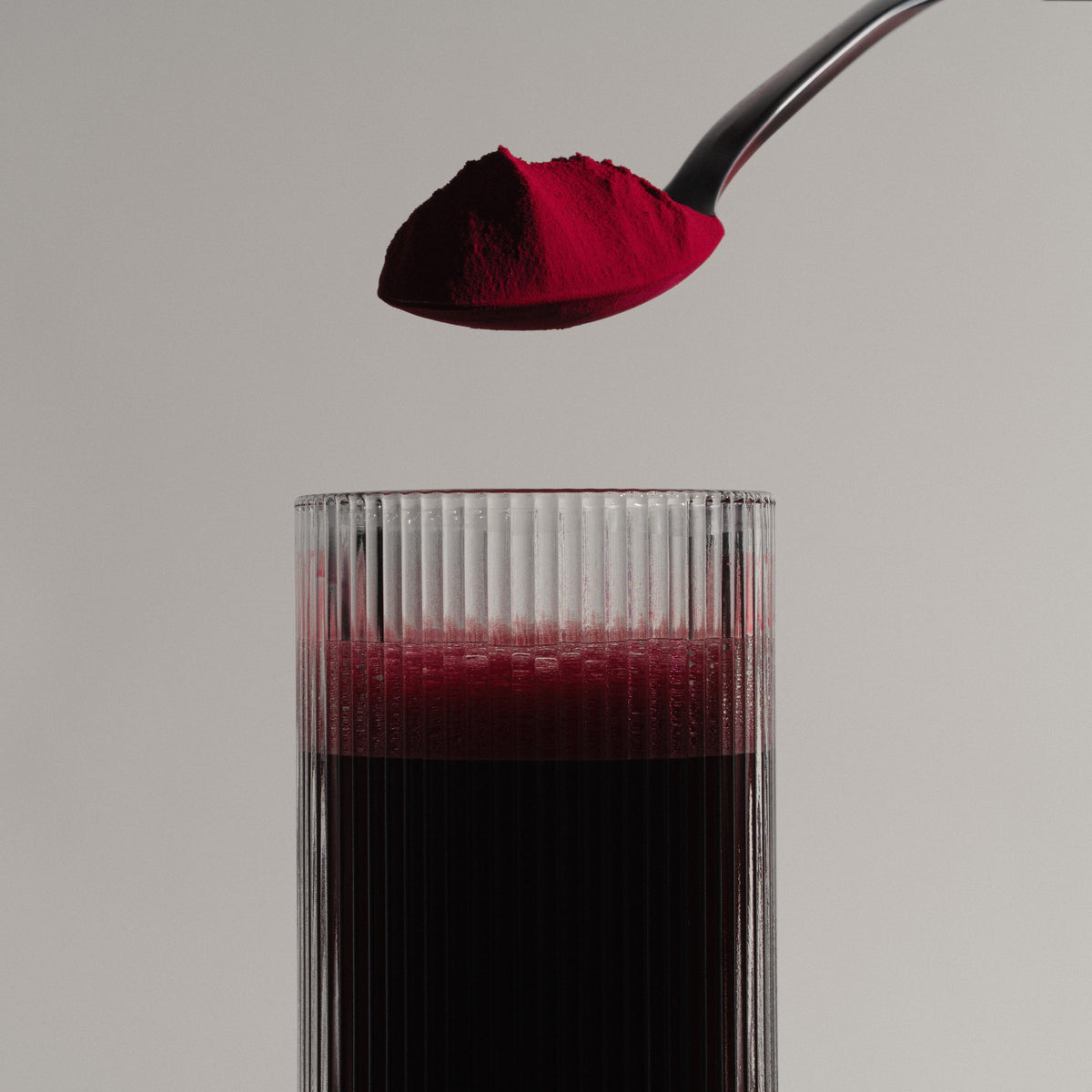 Stamox beetroot sport nutrition powder for VO2 max being poured into a glass of red drink