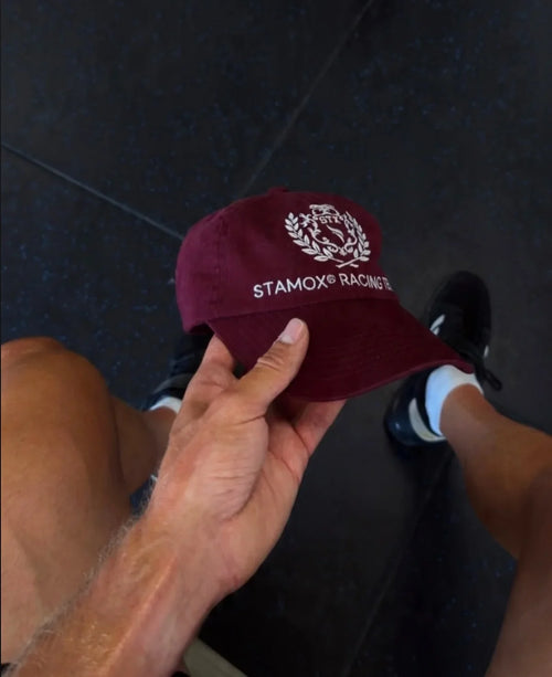 Hand holding a maroon Stamox Racing Team cap for beetroot sport nutrition and vo2 max support