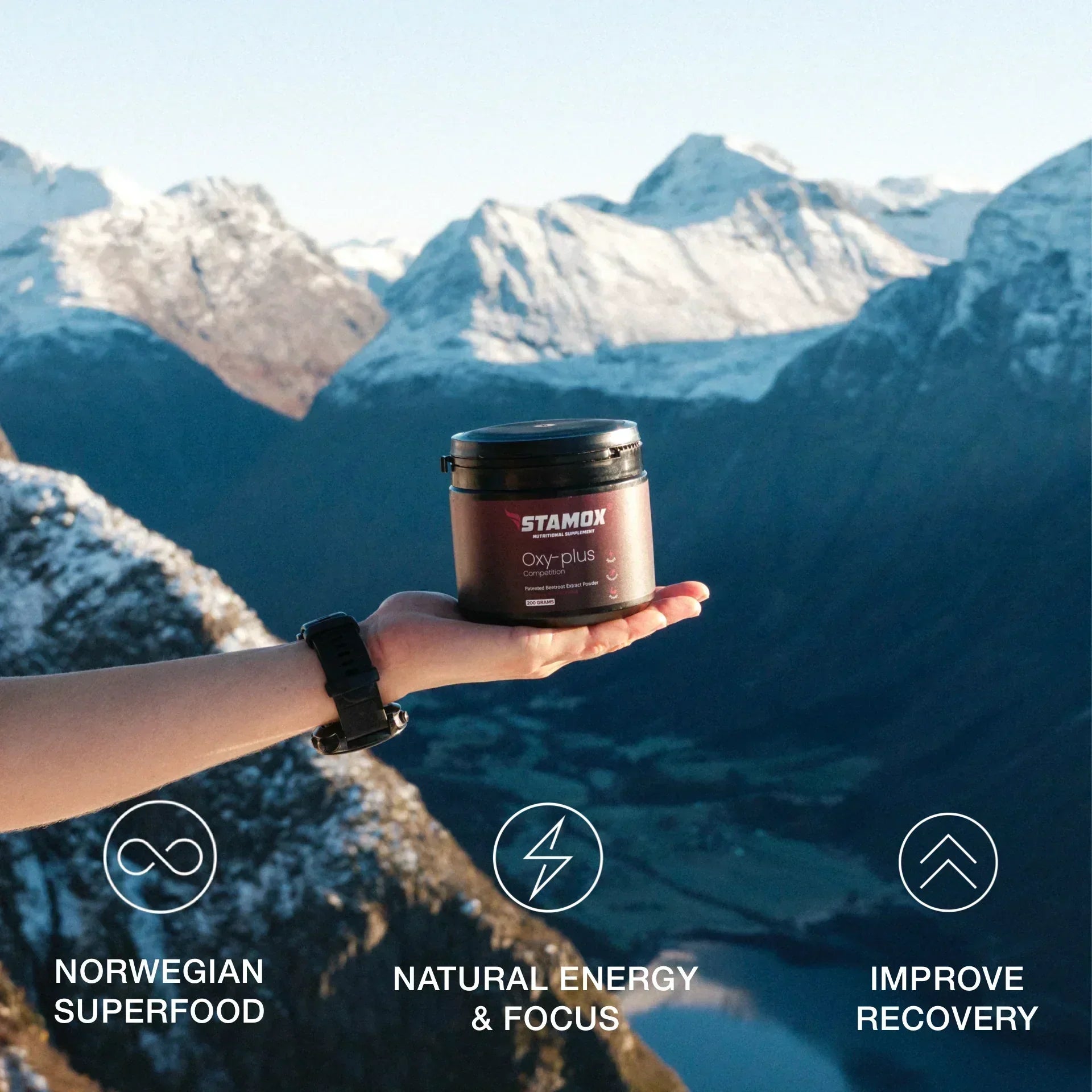 Stamox beetroot powder container held outdoors with snowy mountains in the background