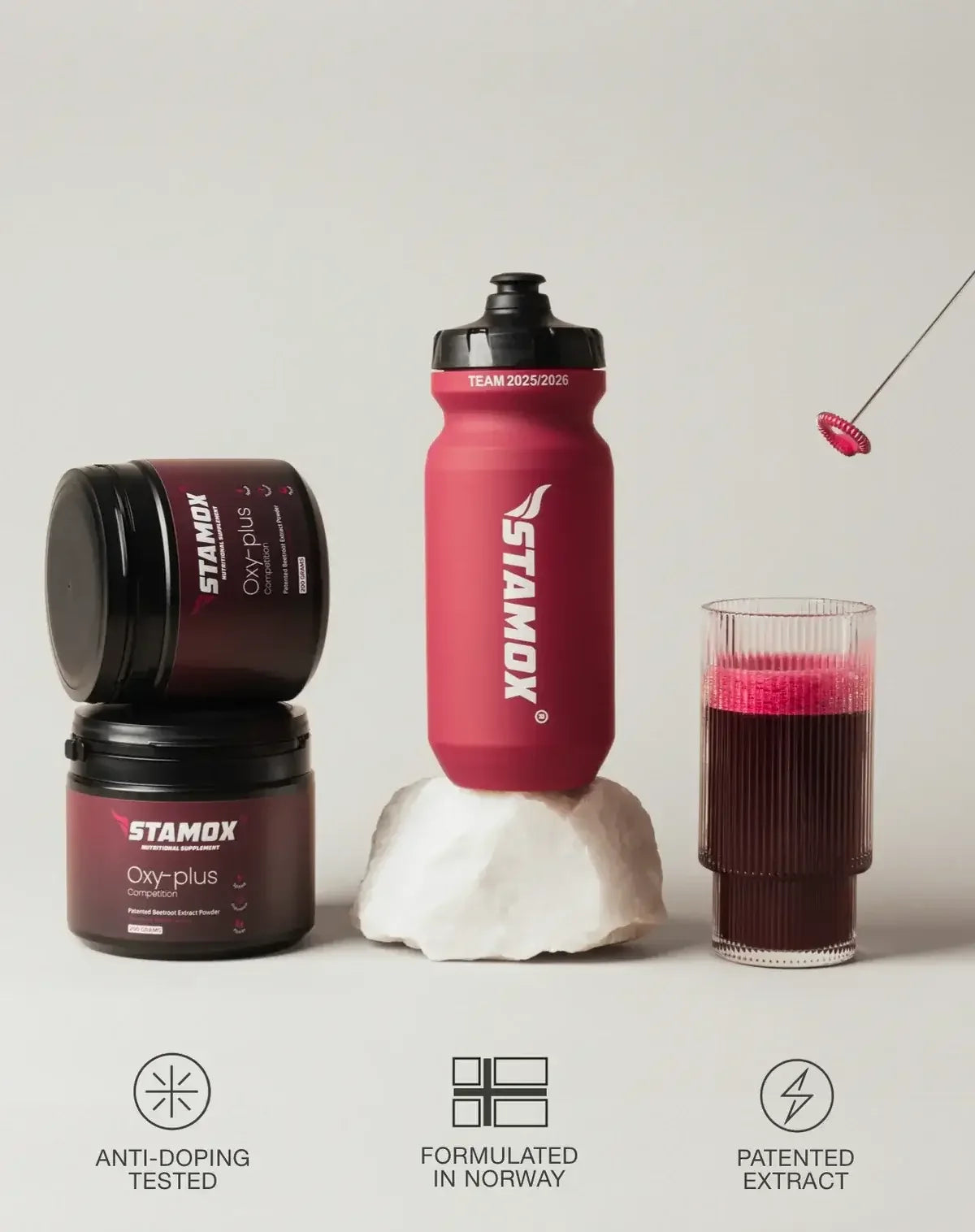 Stamox beetroot powder containers, water bottle, and glass of beetroot drink on cream background