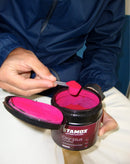 Stamox beetroot powder in black tub, person scooping vibrant pink supplement for endurance and performance.
