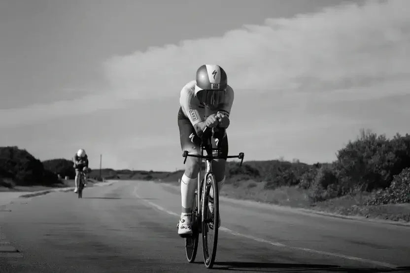 Cyclist in aerodynamic gear racing on road, boosted by stamox beetroot powder for endurance