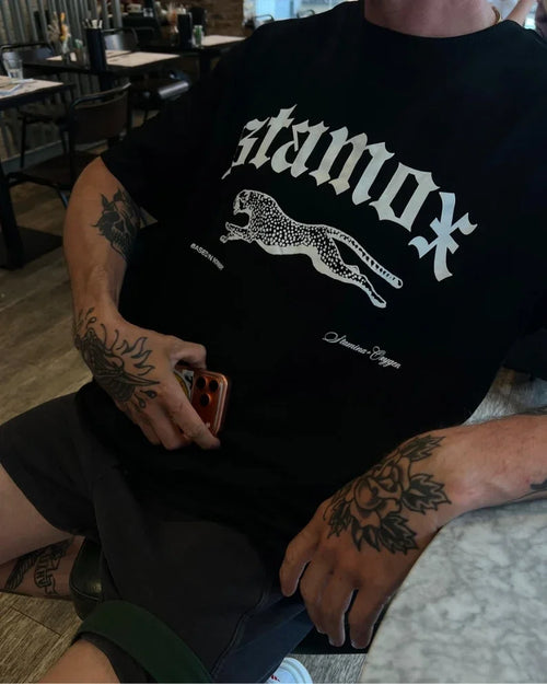 Person wearing a black Stamox beetroot sport nutrition VO2 max t-shirt with a leopard graphic.