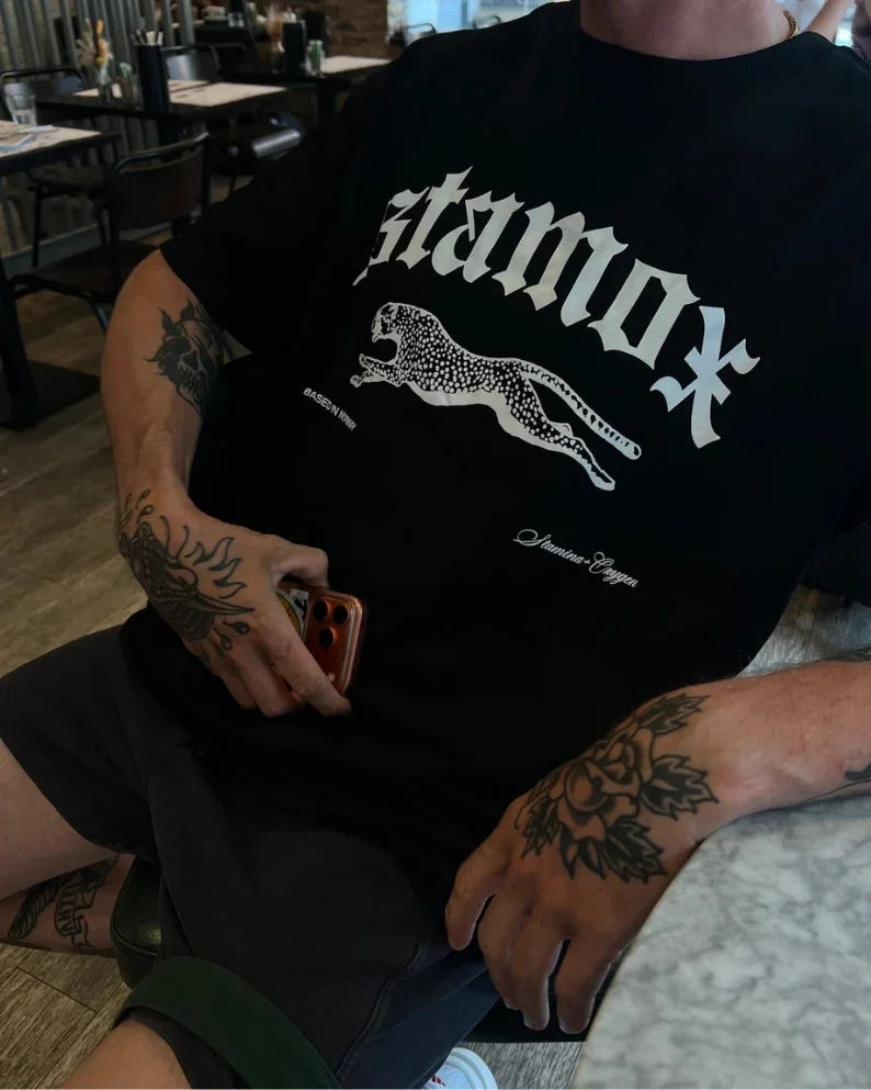 Person wearing a black Stamox beetroot sport nutrition VO2 max t-shirt with a leopard graphic.