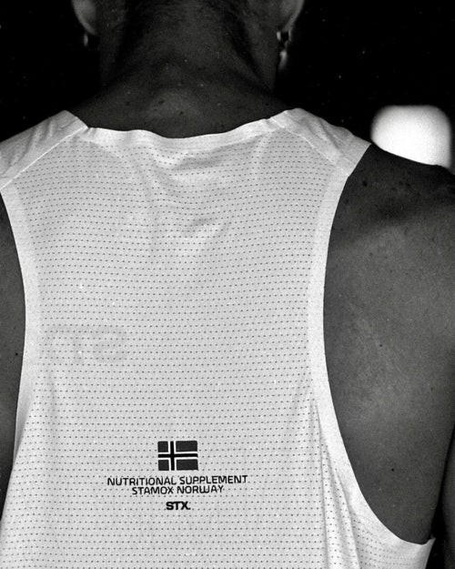 Athlete wearing white tank top branded with Stamox Norway nutritional supplement and stamox beetroot powder